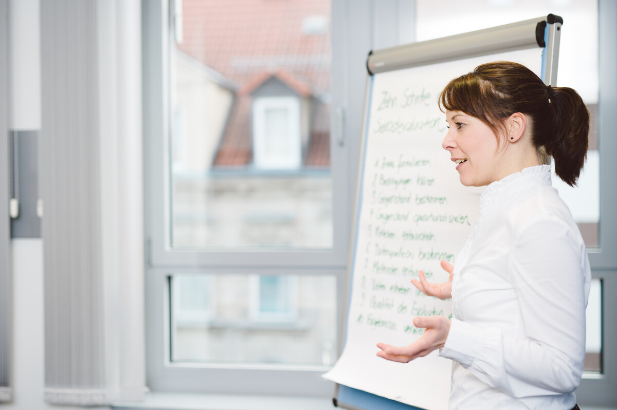 Eine Person hält einen Vortrag vor einem Flipchart