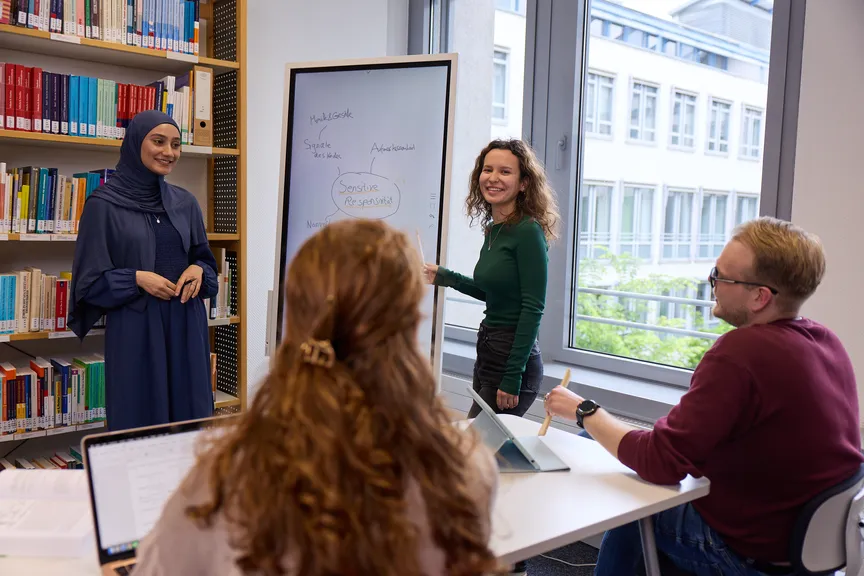 Eine Gruppe Studierender macht eine Gruppenarbeit in einer Bibliothek