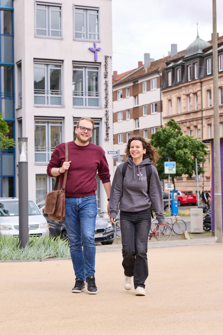 Zwei Studierende laufen auf einem Platz vor der EVHN