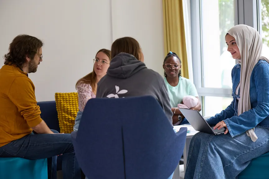 Einige Studierende sitzen in einer Sitzgruppe und unterhalten sich