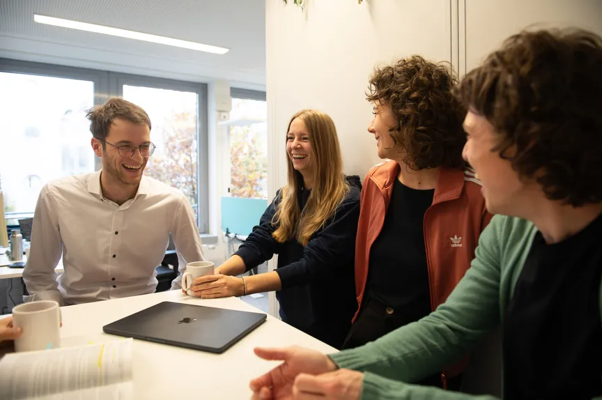 Einige Studiernde stehen in einer Gruppe und unterhalten sich fröhlich