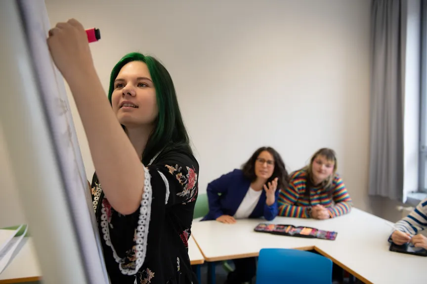 Eine Studierende schreibt in einem Seminar auf ein Flipchart