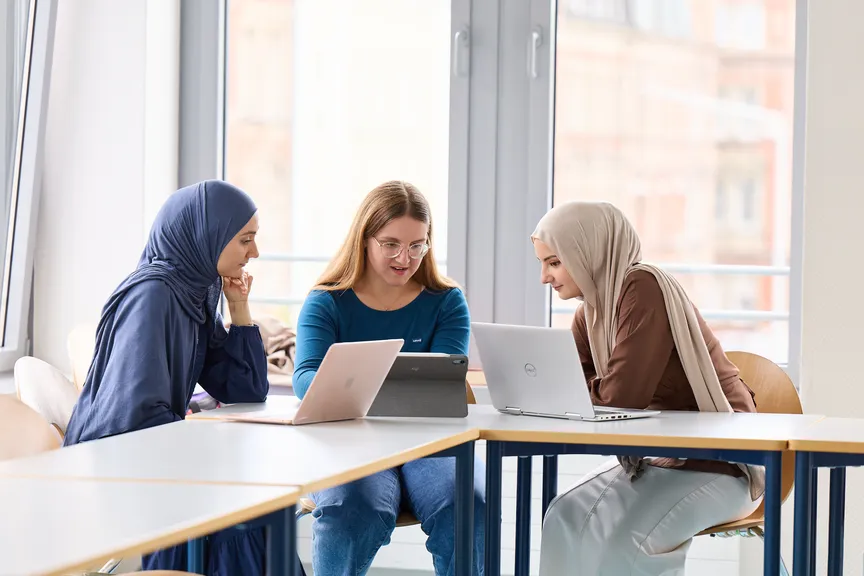 Eine Gruppe Studierender arbeitet an Laptops