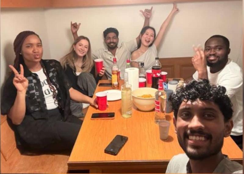 6 junge Menschen sitzen um einen Esstisch