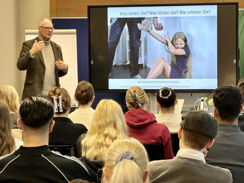 Prof. Dr. Arne Manzesche referiert, Zuhörerinnen und Zuhörer sitzen in Reihen