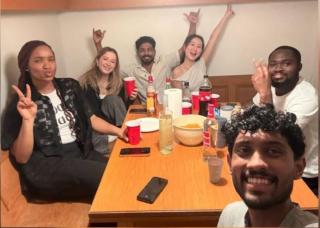 6 junge Menschen sitzen um einen Esstisch