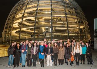 Studierende und Schülerinnen und Schüler vor der abendlich beleuchteten Kuppel des Reichstagsggebäudes mit Tessa Ganserer